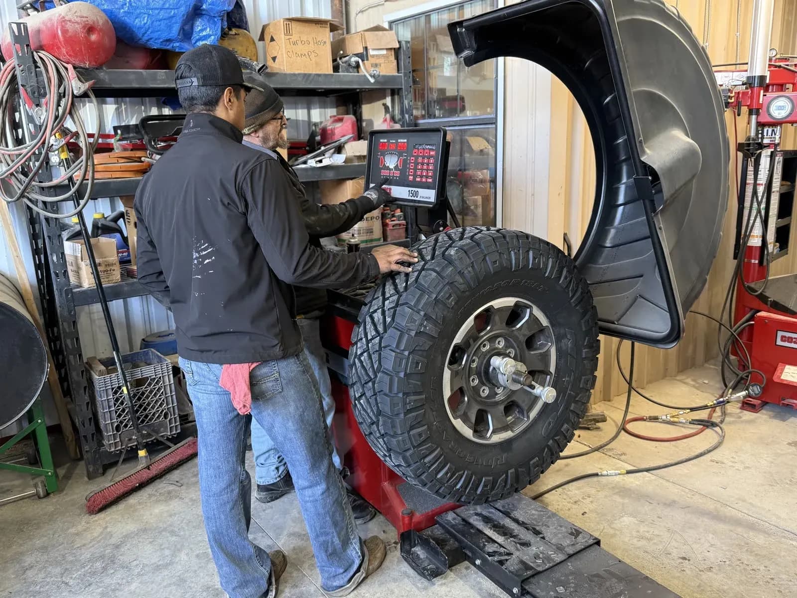 Technician balancing an off-road wheel and tire on the shop balancer