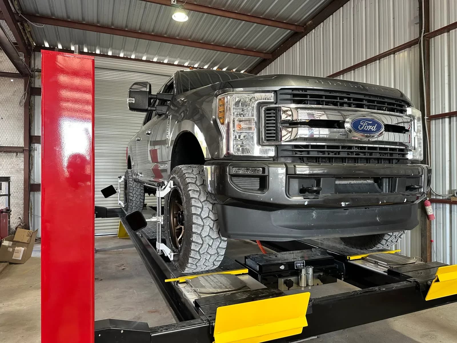 Lifted Ford F-250 on the alignment rack with alignment targets at Quality Mechanics