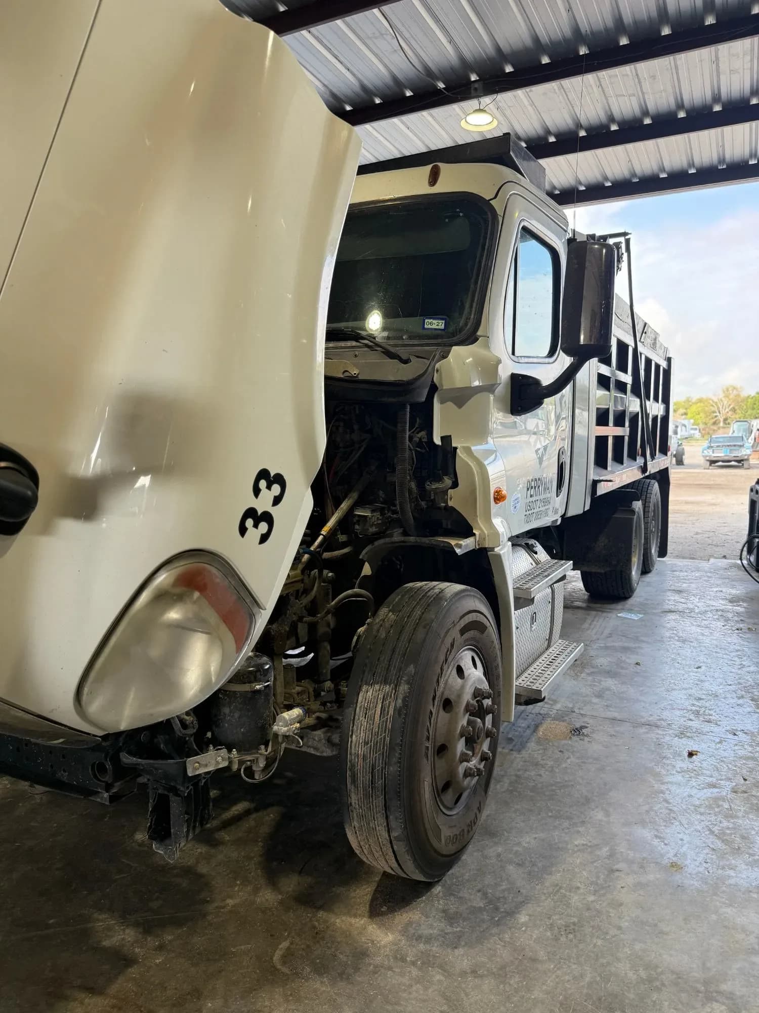 Dump truck with the hood tilted open for diagnostics in the Quality Mechanics shop