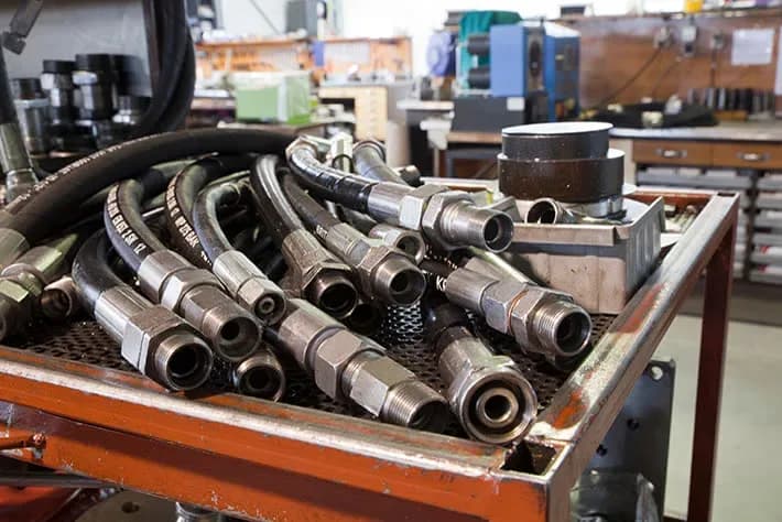 Completed hydraulic hose assemblies with crimped fittings on the fabrication bench