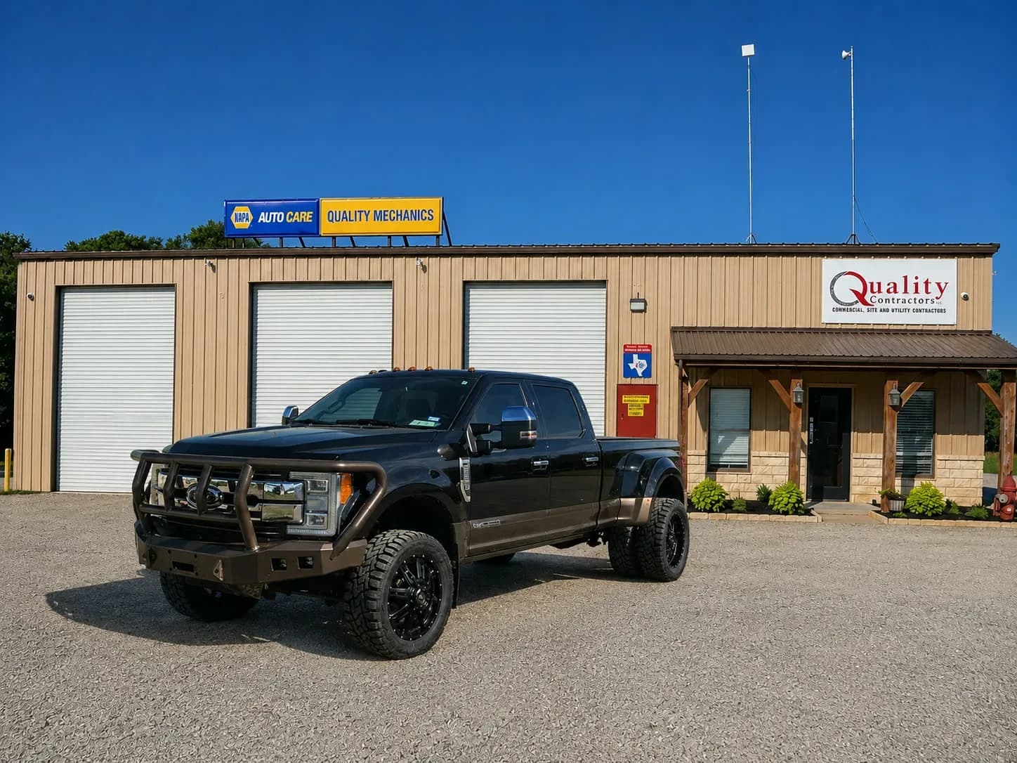 Lifted Ford F-450 King Ranch dually with grille-guard replacement front bumper in front of the Quality Mechanics shop in Waco