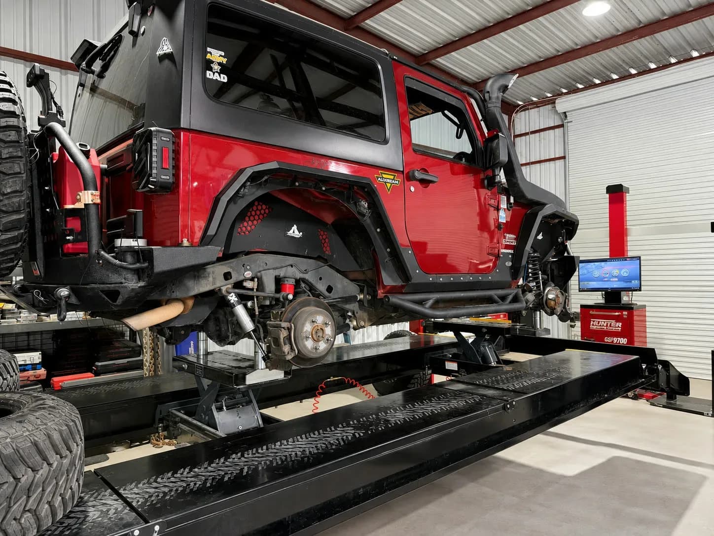 Lifted Jeep Wrangler with off-road suspension and armor on the alignment rack at Quality Mechanics